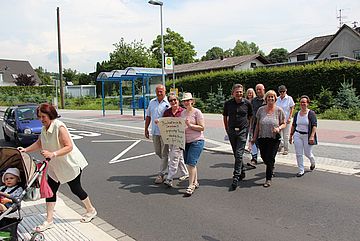 Einweihung der neuen Bushaltestellt: Bürgermeister Klaus Pipke (6.v.l. hintere Gruppe) beim Überqueren der K40. Cornelia Miethe (Mitte vordere Gruppe) freut sich mit allen Beteiligten.