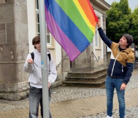 Bürgermeister Mario Dahm hisst gemeinsam mit einem Schüler die Regenbogenflagge am Historischen Rathaus als Zeichen für Vielfalt, Respekt und Akzeptanz