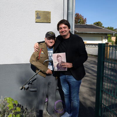 Russell Sattazahn zusammen mit Bürgermeister Mario Dahm vor der Ehrentafel in Uckerath. Russell Sattazahn zusammen mit Bürgermeister Mario Dahm vor der Ehrentafel in Uckerath.