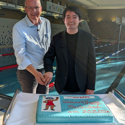 Sascha Hendrich-Bächer und Mario Dahm schneiden die Torte an, die in der Küche der Sportschule zur Wiedereröffnung gebacken wurde